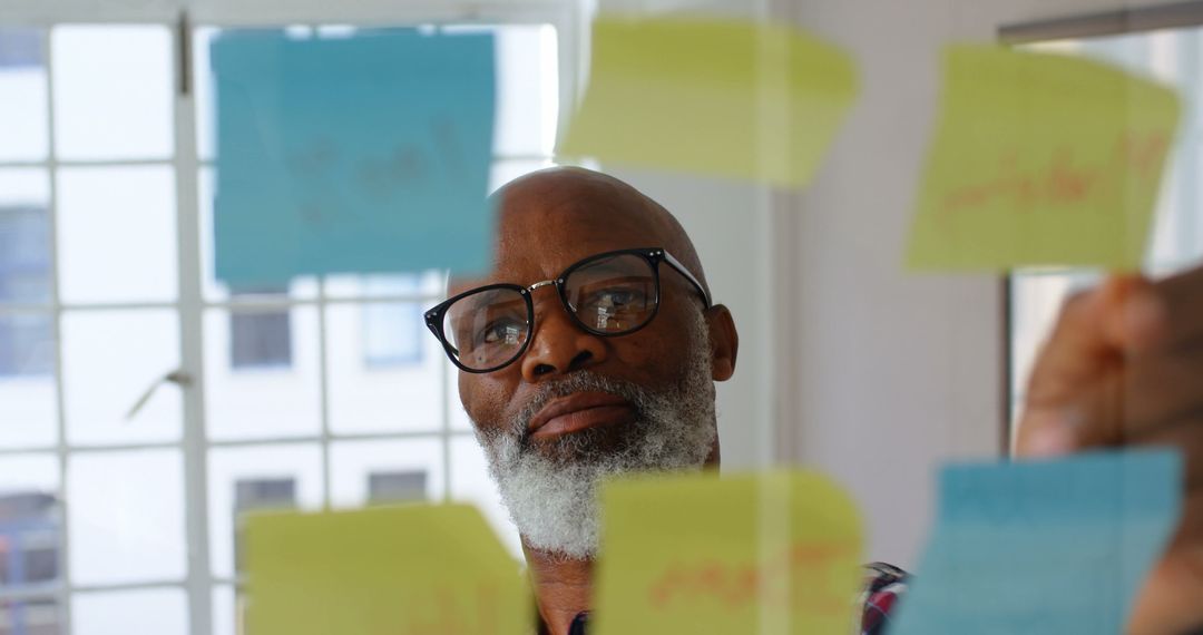 Focused Businessman Analyzing Sticky Notes for Strategic Planning