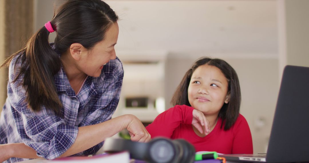 Asian Mother Helping Daughter with Homework at Home