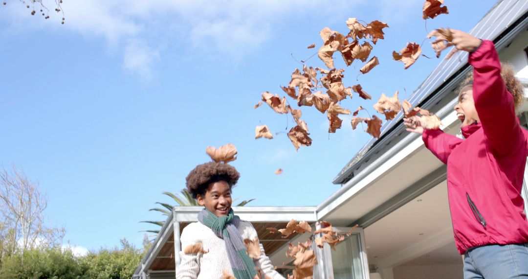 Happy Mother and Son Playing with Leaves in Autumn Garden