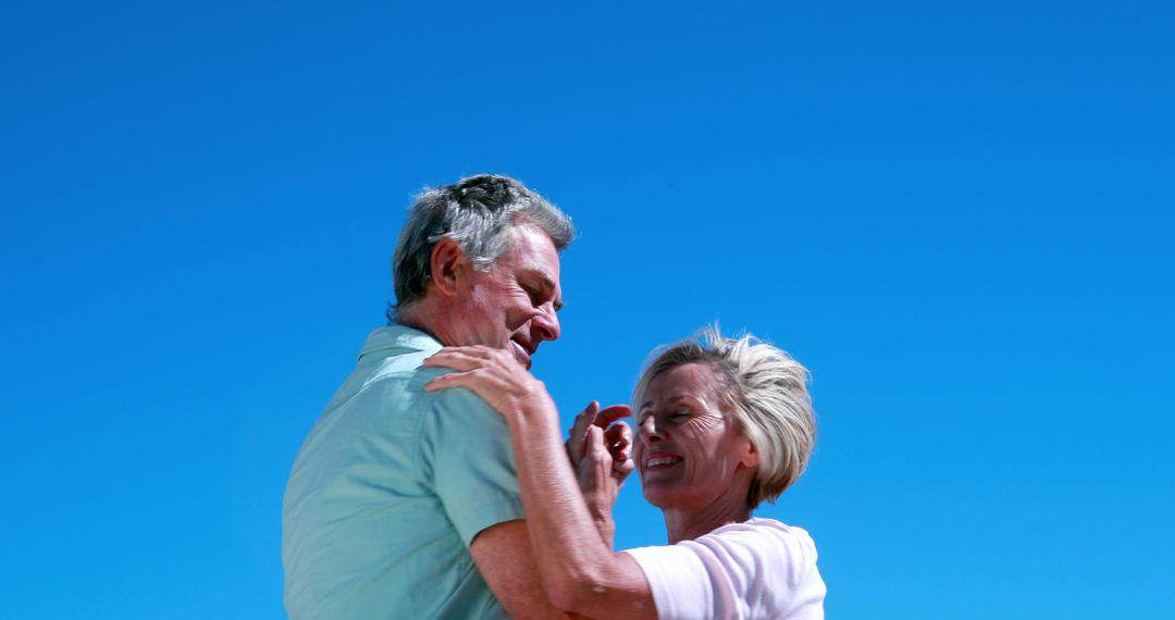 Happy Elderly Couple Dancing Outdoors with Clear Blue Sky - Free Images, Stock Photos and Pictures on Pikwizard.com