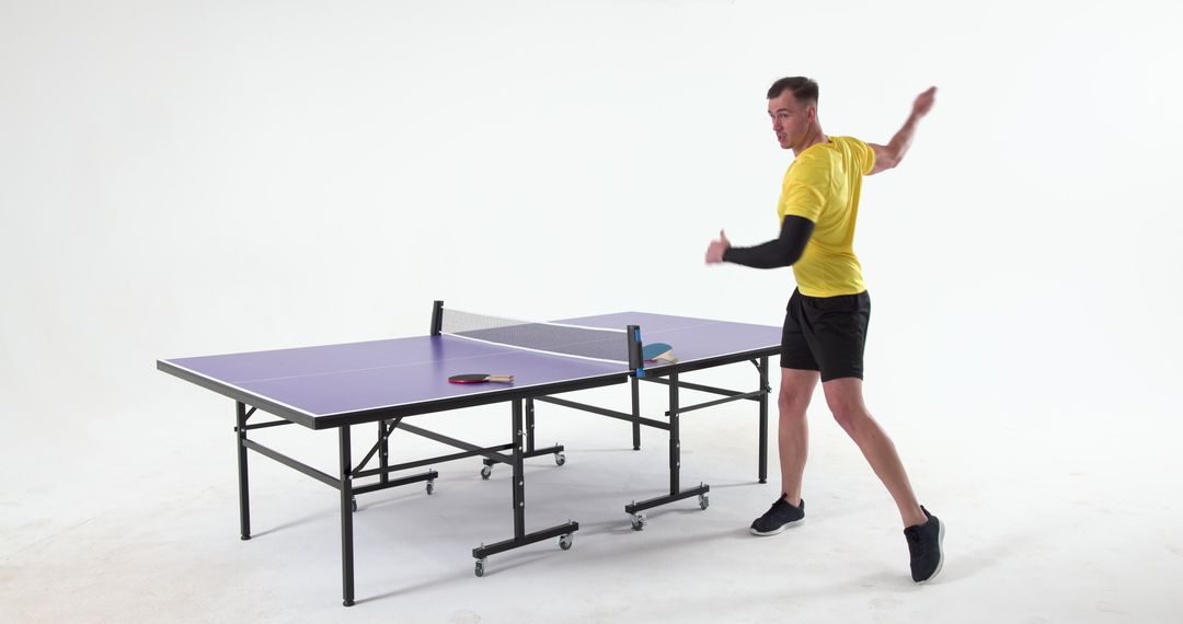 Athlete in Studio Swinging Paddle Next to Tactical Ping Pong Table