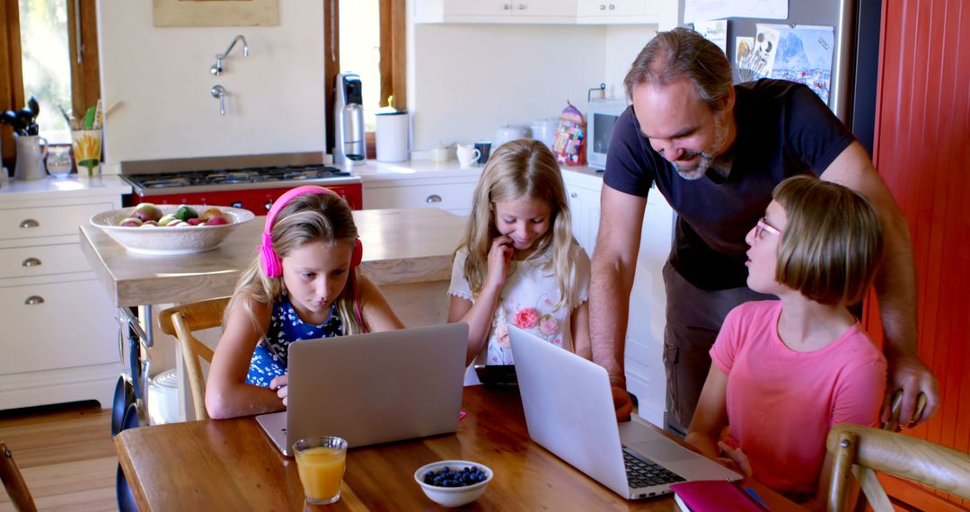 Father Helping Daughters with Homework on Laptops in Kitchen - Free Images, Stock Photos and Pictures on Pikwizard.com