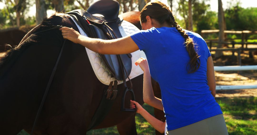 Woman Adjusting Saddle on Horse Outdoors in Daylight - Free Images, Stock Photos and Pictures on Pikwizard.com