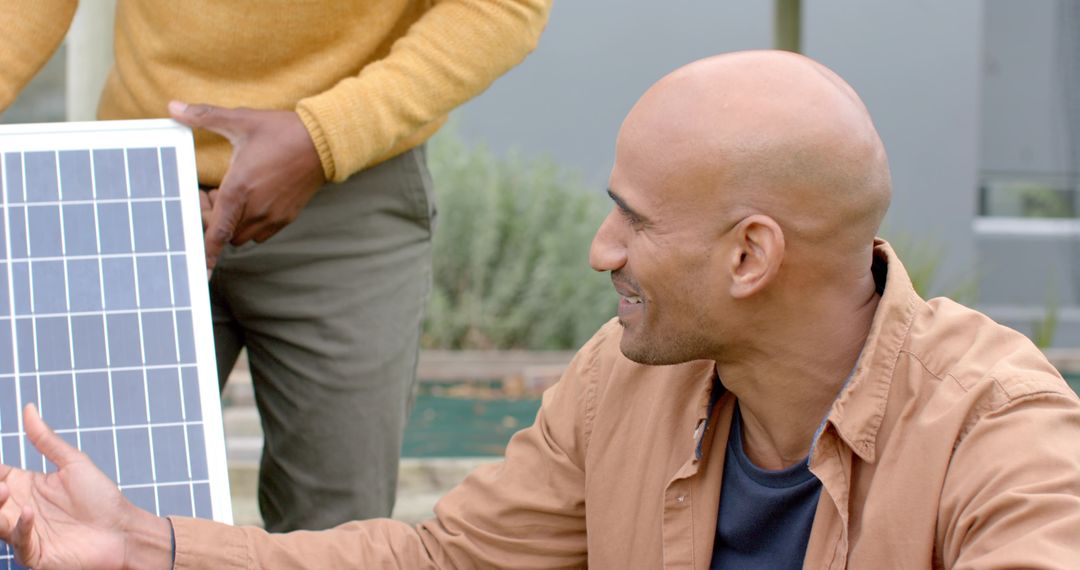 Diverse Male Coworkers Inspecting Solar Panel in Garden Collaborating on Installation