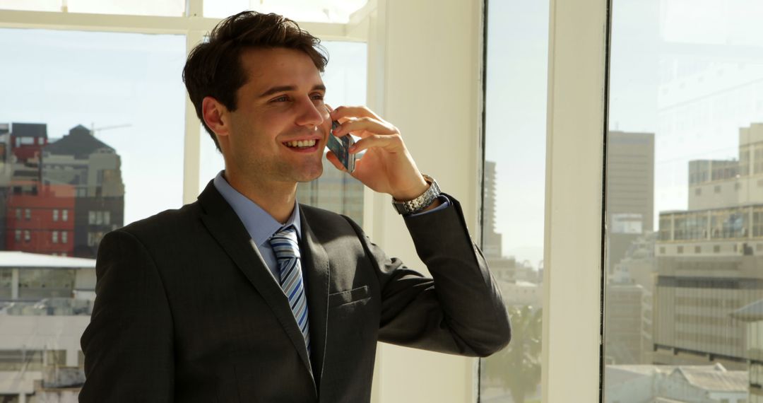 Smiling Businessman Talking on Smartphone in Modern Office with City View - Free Images, Stock Photos and Pictures on Pikwizard.com