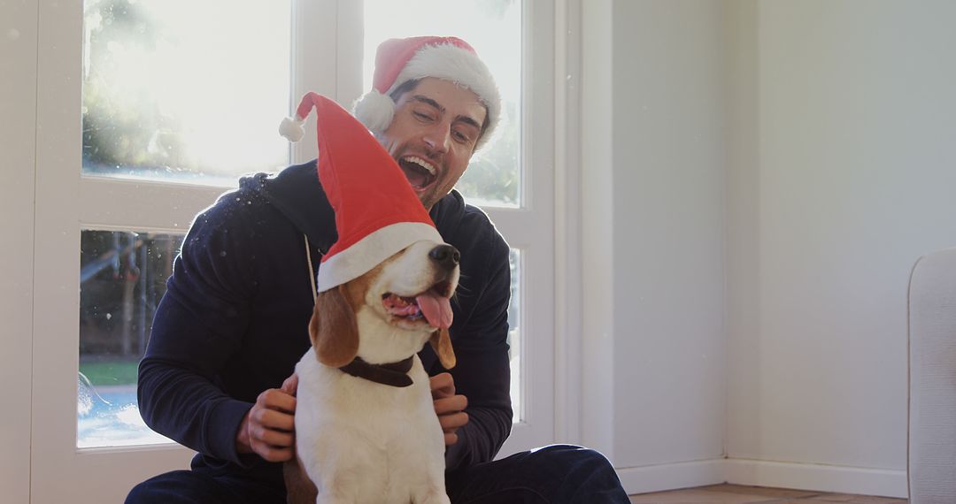 A man and his beagle in Santa hats joyfully celebrate Christmas. - Free Images, Stock Photos and Pictures on Pikwizard.com