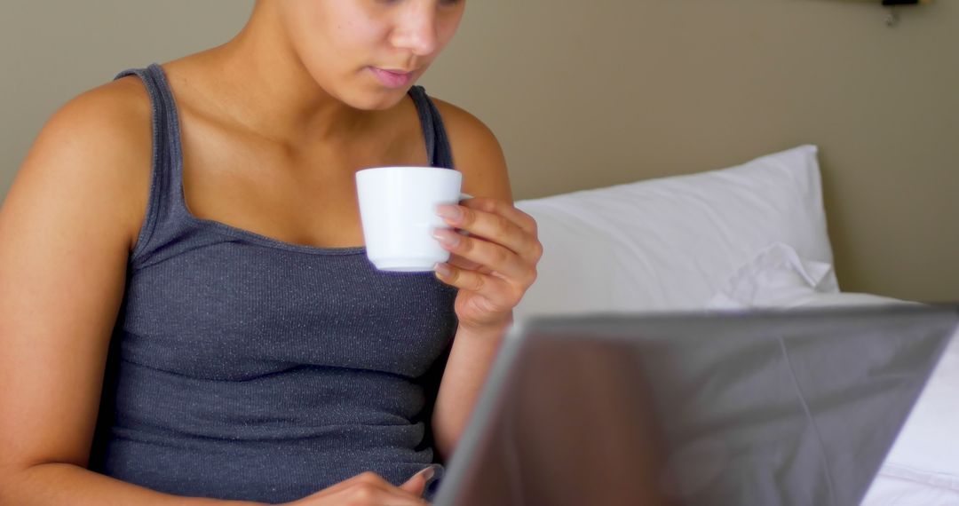 Young Woman Drinking Coffee While Working on Laptop in Bed - Free Images, Stock Photos and Pictures on Pikwizard.com