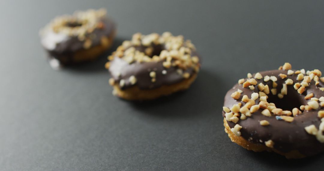 Three Chocolate Donuts with Nut Toppings on Black Background - Free Images, Stock Photos and Pictures on Pikwizard.com