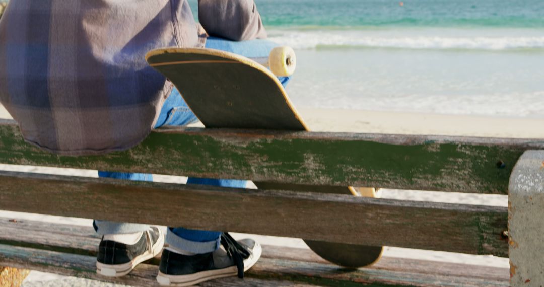 Young Skateboarder Sitting on Beach Bench Looking at Ocean - Free Images, Stock Photos and Pictures on Pikwizard.com