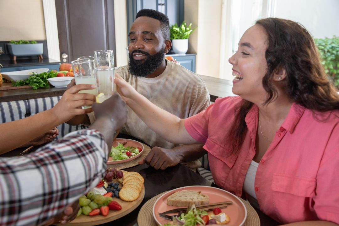 Diverse Friends Enjoying Fresh Meal and Toasting at Home Celebration