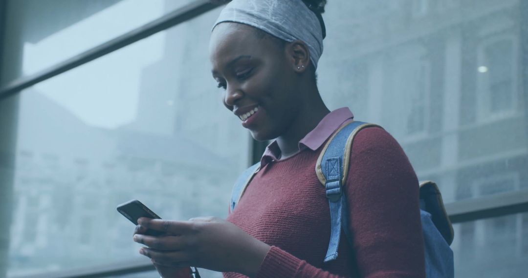 Smiling Woman Wearing Headwrap Using Smartphone At Urban Transit Hub