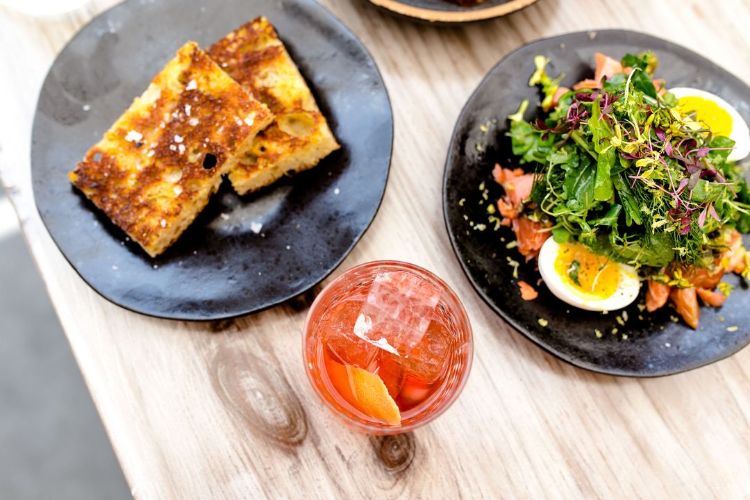Brunch spread featuring charred focaccia, smoked salmon salad with soft egg and Negroni
