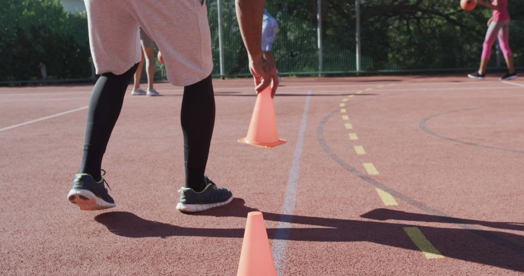 Athletes Preparing Training Setup with Cones on Outdoor Track - Free Images, Stock Photos and Pictures on Pikwizard.com