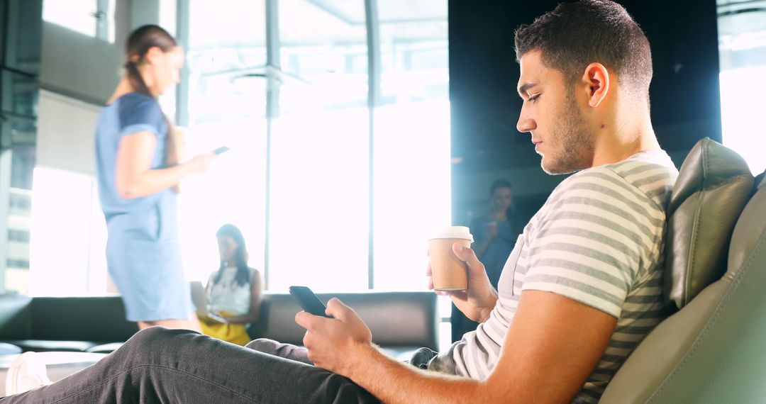 Man Relaxing with Coffee and Smartphone in Modern Office Lounge - Free Images, Stock Photos and Pictures on Pikwizard.com