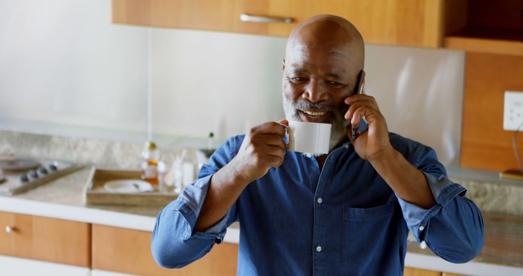 Mature Man Drinking Coffee and Talking on Phone in Modern Kitchen - Free Images, Stock Photos and Pictures on Pikwizard.com