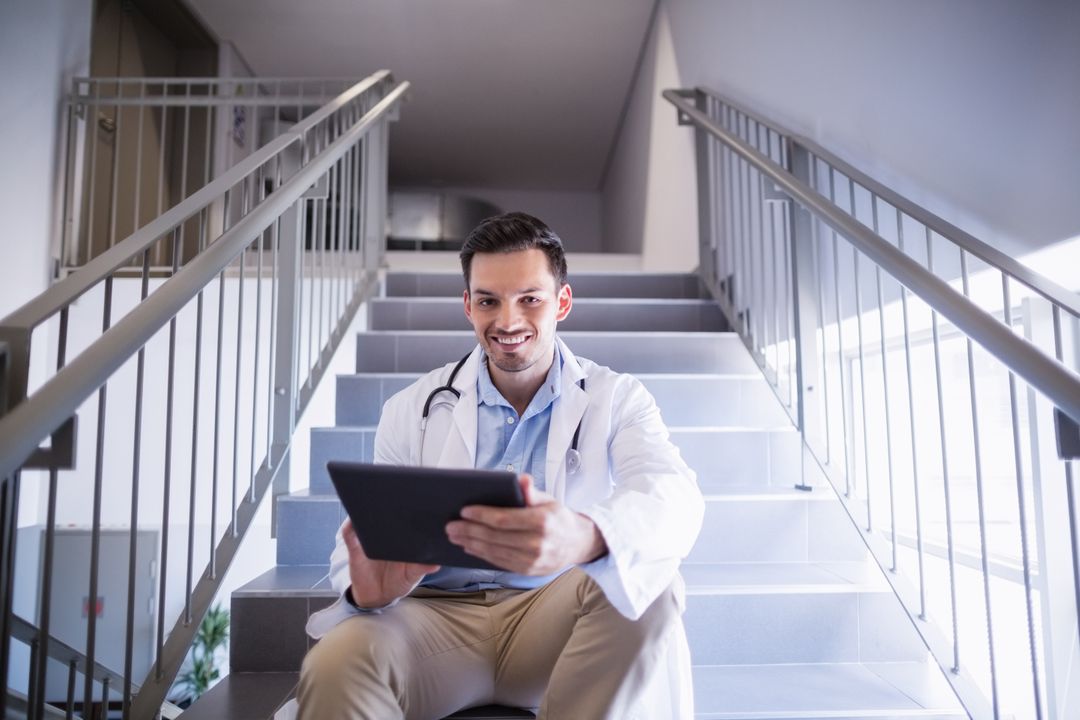 Portrait of doctor sitting on staircase using digital tablet - Free Images, Stock Photos and Pictures on Pikwizard.com