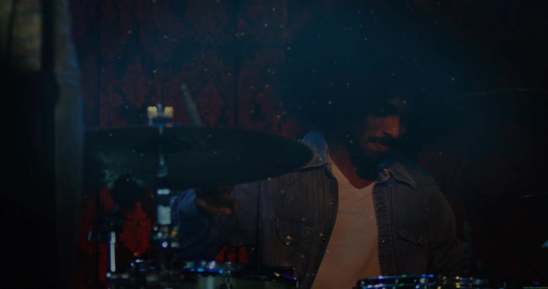 Drummer in Denim Jacket Performing on Dimly Lit Stage
