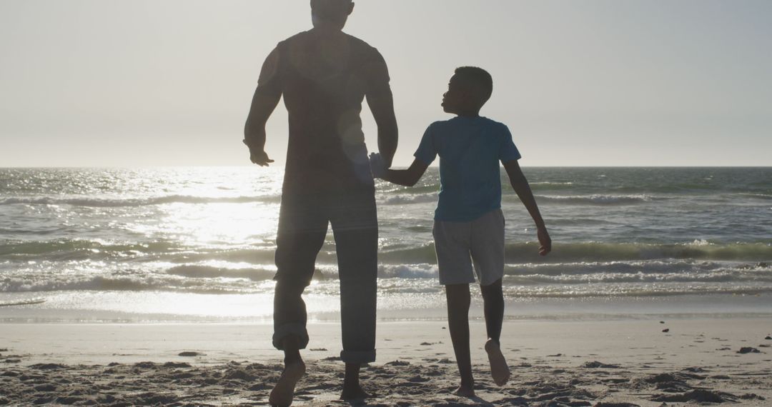 Father and Son Walking Together on Beach at Sunset - Free Images, Stock Photos and Pictures on Pikwizard.com