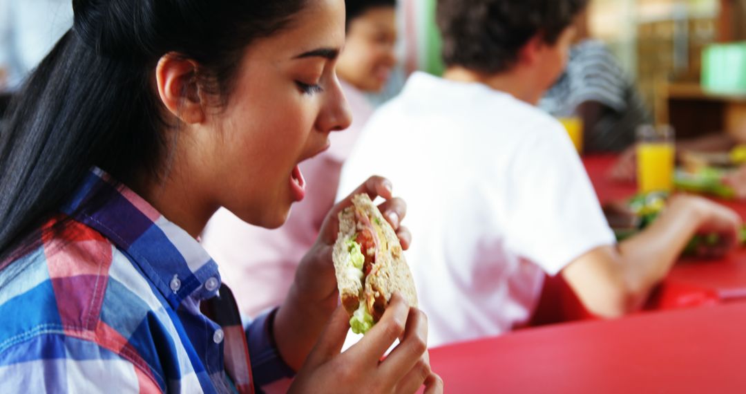 Teenager Enjoying Sandwich in Cafeteria - Free Images, Stock Photos and Pictures on Pikwizard.com