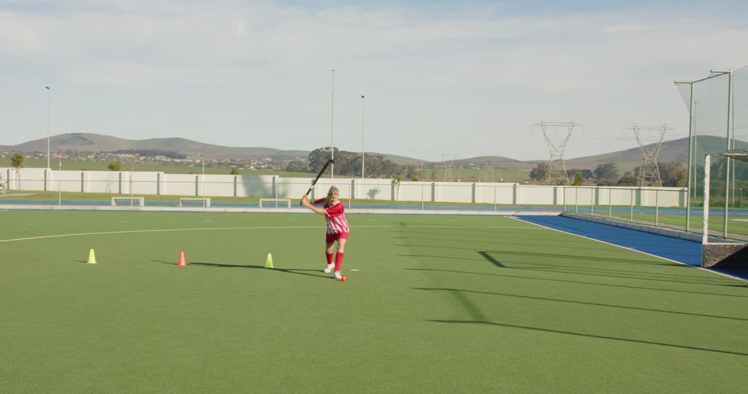 Female Hockey Player Practicing On Pitch With Focused Shot