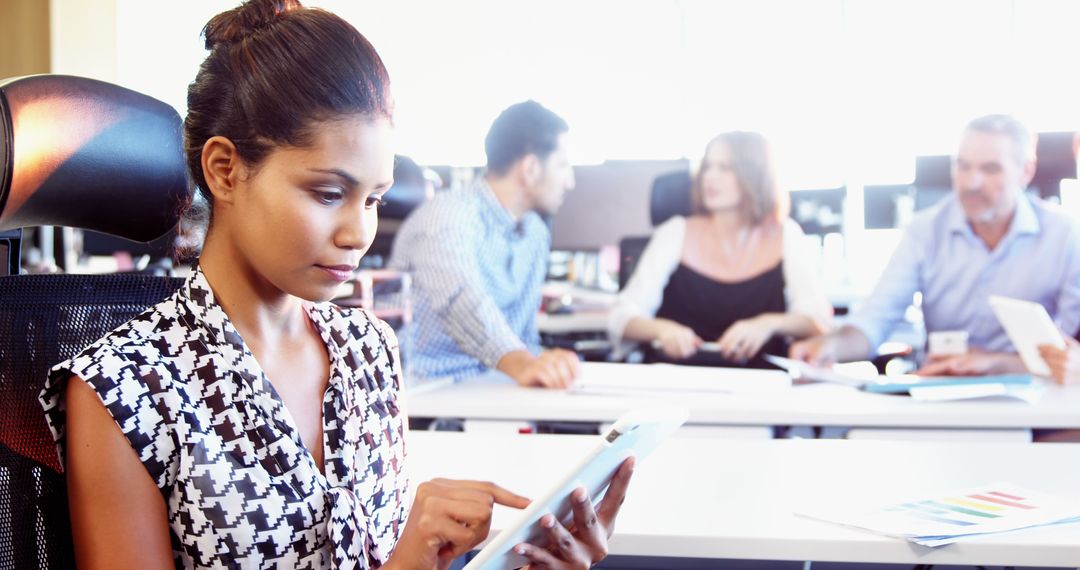 Focused Woman Using Tablet in Busy Office Environment