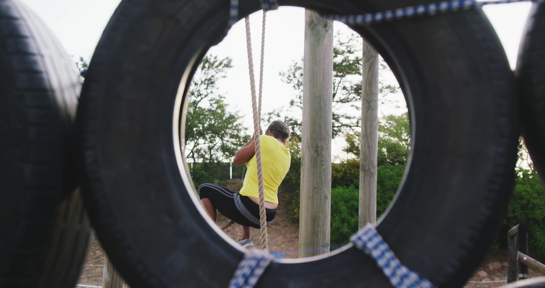 Woman Training on Rope Course Beneath Tire Ring in Outdoor Boot Camp