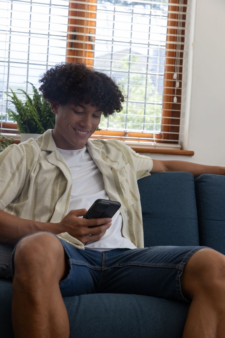 Smiling African American Man Relaxing with Smartphone on Couch