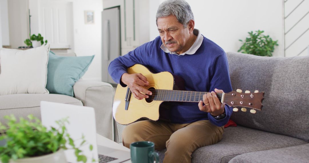 Image of happy senior biracial man using laptop and playing acoustic guitar at home - Free Images, Stock Photos and Pictures on Pikwizard.com