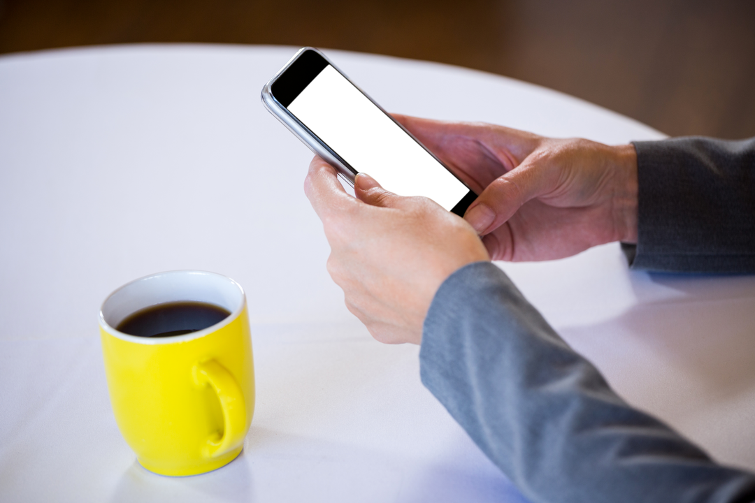 Transparent Smartphone Usage Near Yellow Coffee Mug in Café - Download Free Stock Images Pikwizard.com