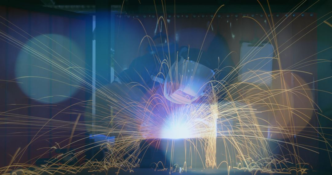 Welder Working in Industrial Workshop with Sparks