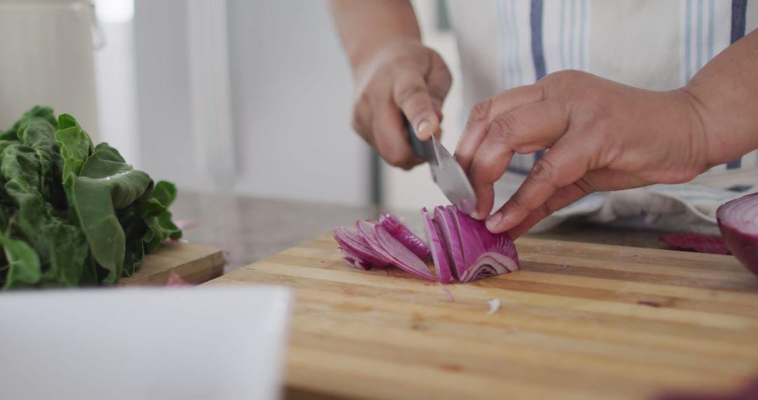 Close-Up of Hands Chopping Red Onion on Wooden Cutting Board in Kitchen - Free Images, Stock Photos and Pictures on Pikwizard.com