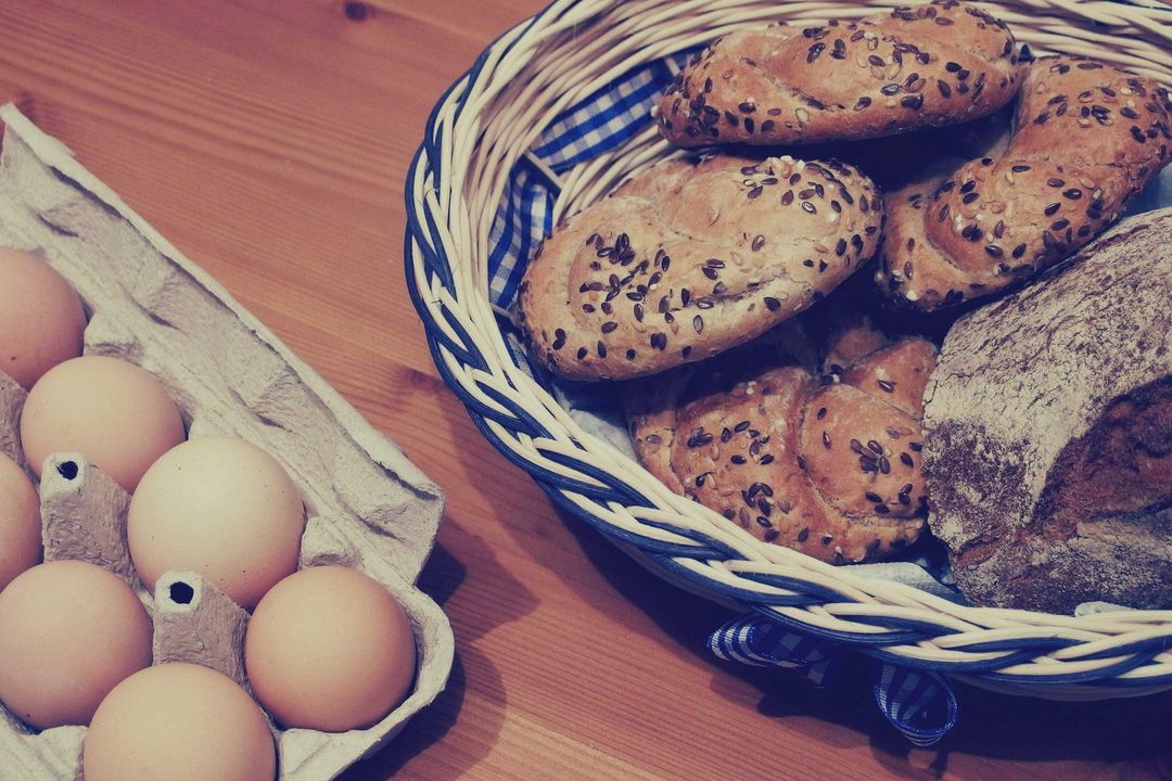 Rustic Basket of Fresh Bread with Eggs on Wooden Surface