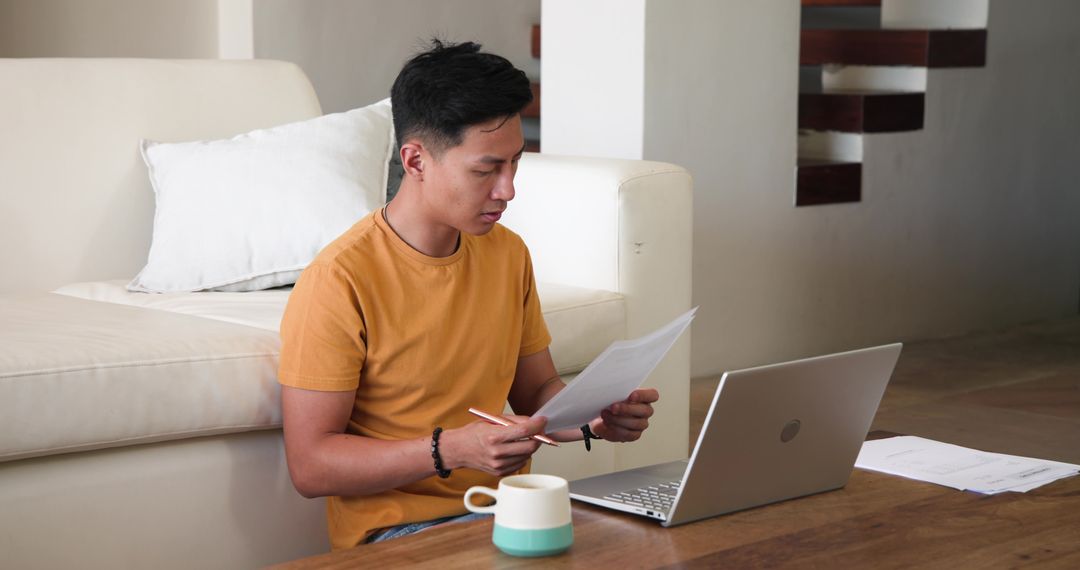 Young Man Reviewing Documents While Working Remote in Cozy Environment