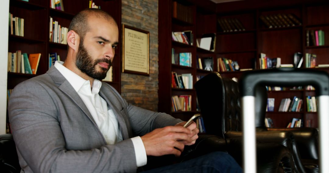 Businessman Checking Smartphone in Library Lounge - Free Images, Stock Photos and Pictures on Pikwizard.com