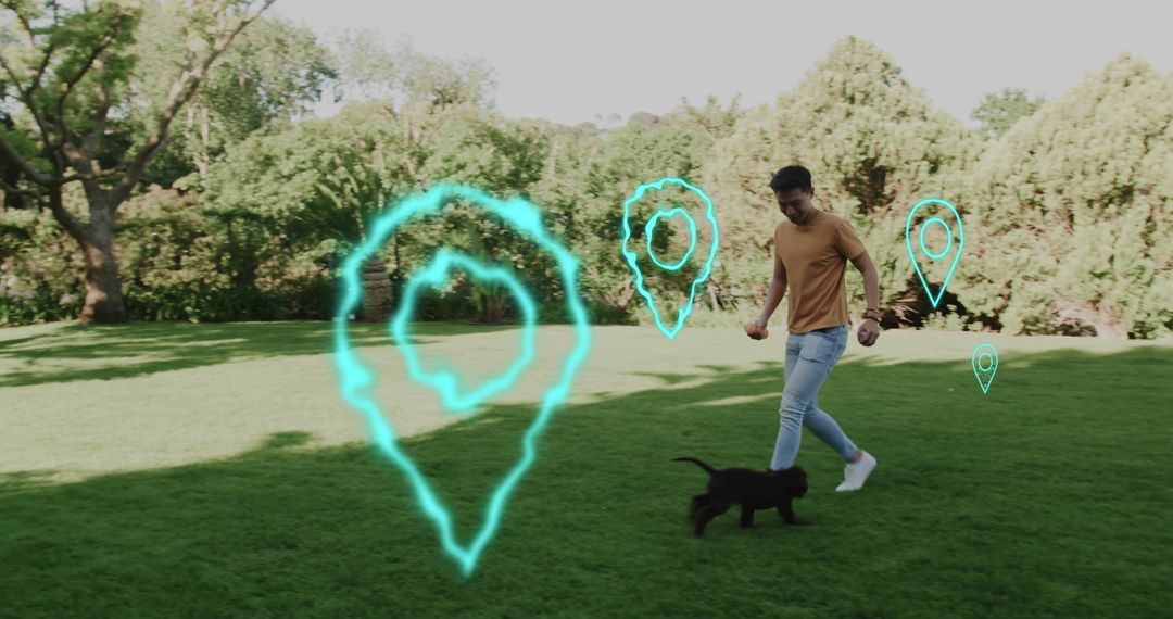 Young man walking and playing with black puppy in park with glowing location pins