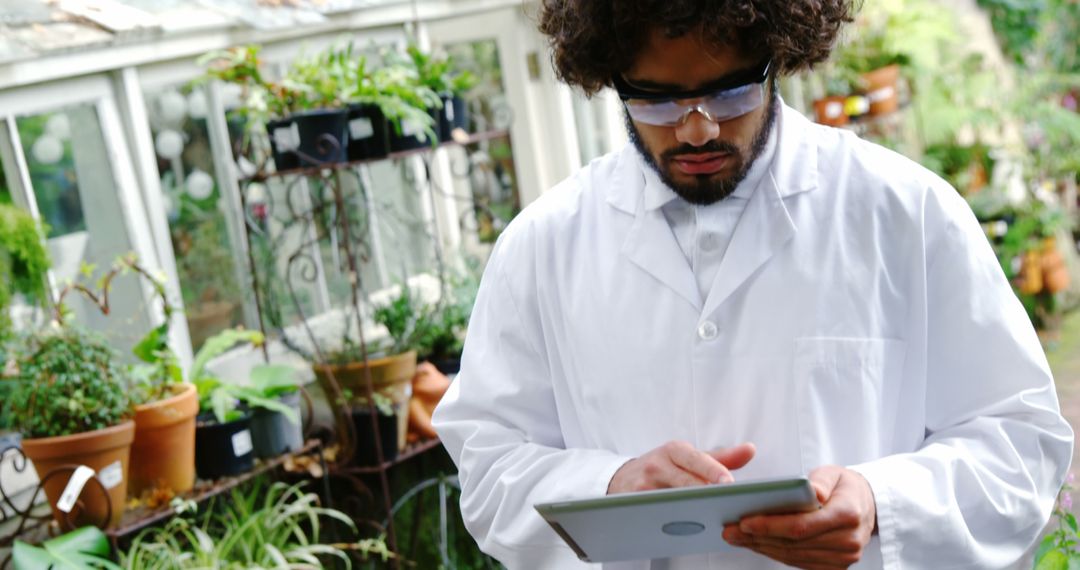 Botanist Using Tablet in Greenhouse Wearing Lab Coat - Free Images, Stock Photos and Pictures on Pikwizard.com