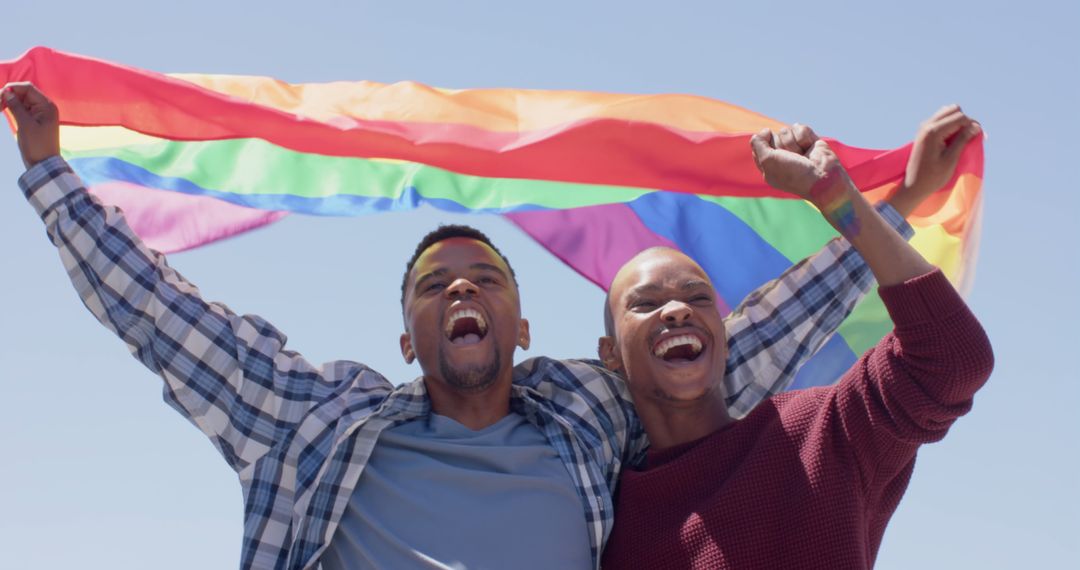 Happy african american gay male couple celebrating with pride flag outdoors in the sun - Free Images, Stock Photos and Pictures on Pikwizard.com