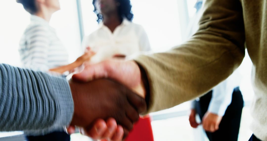 Professional Handshake in Corporate Environment with Diverse Team