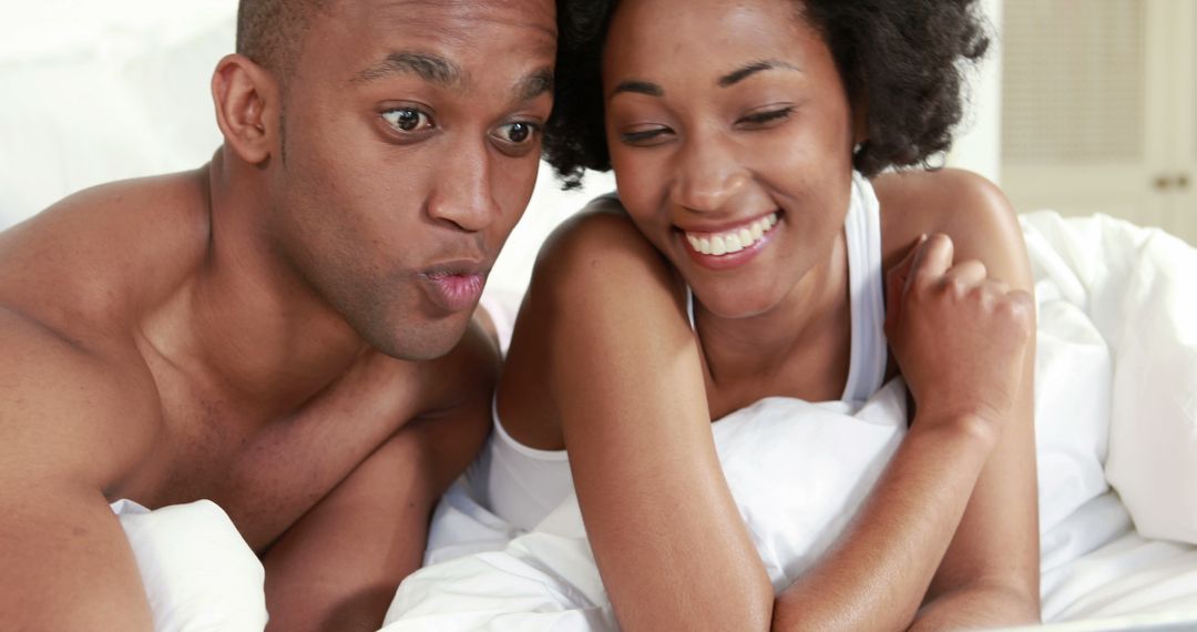 Couple Relaxing in Bed with Smiles and Joyful Expressions