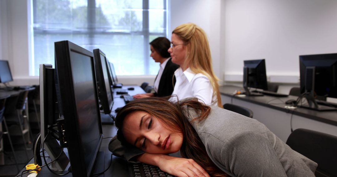 Exhausted Professional Resting in Computer Lab Amidst Busy Colleagues - Free Images, Stock Photos and Pictures on Pikwizard.com