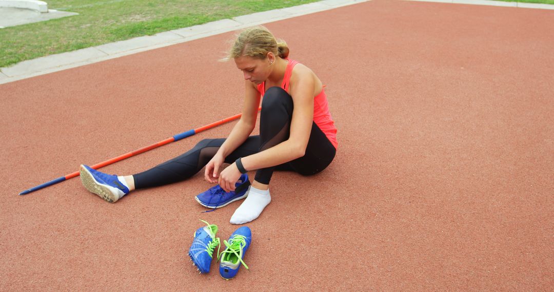 Female athlete tying shoelaces on athletics track - Free Images, Stock Photos and Pictures on Pikwizard.com