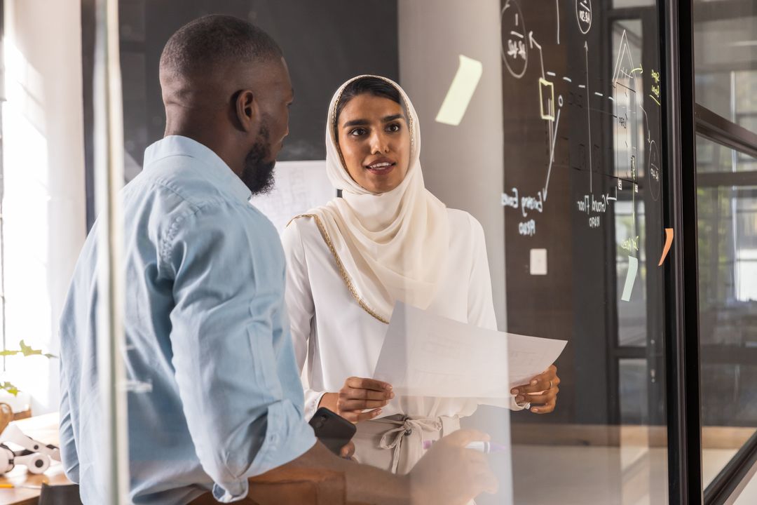 Diverse Coworkers Discussing Project Near Glass Board