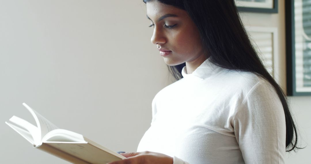 Young Woman Reading Book in Bright Room - Free Images, Stock Photos and Pictures on Pikwizard.com