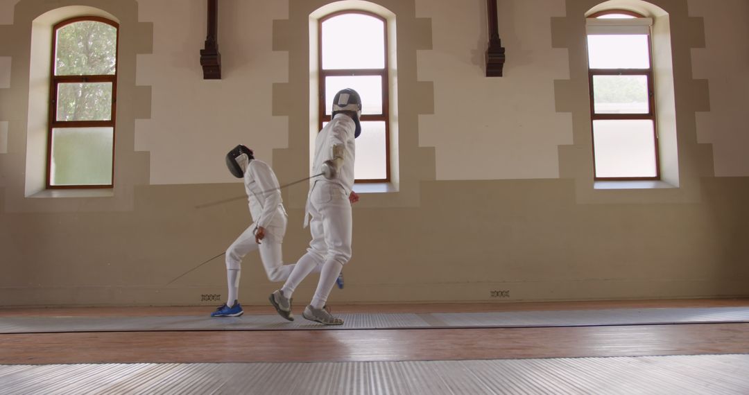 Fencing Training as Two Male Swordsmen Duel on Mat