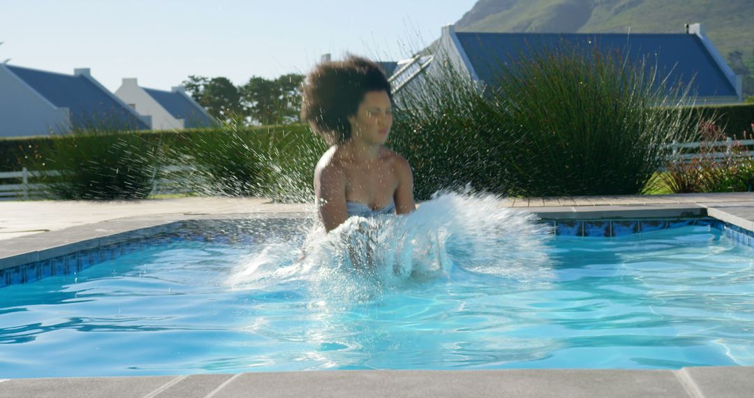 Playful Splashing in Sunny Outdoor Pool by Energetic Young Woman - Free Images, Stock Photos and Pictures on Pikwizard.com