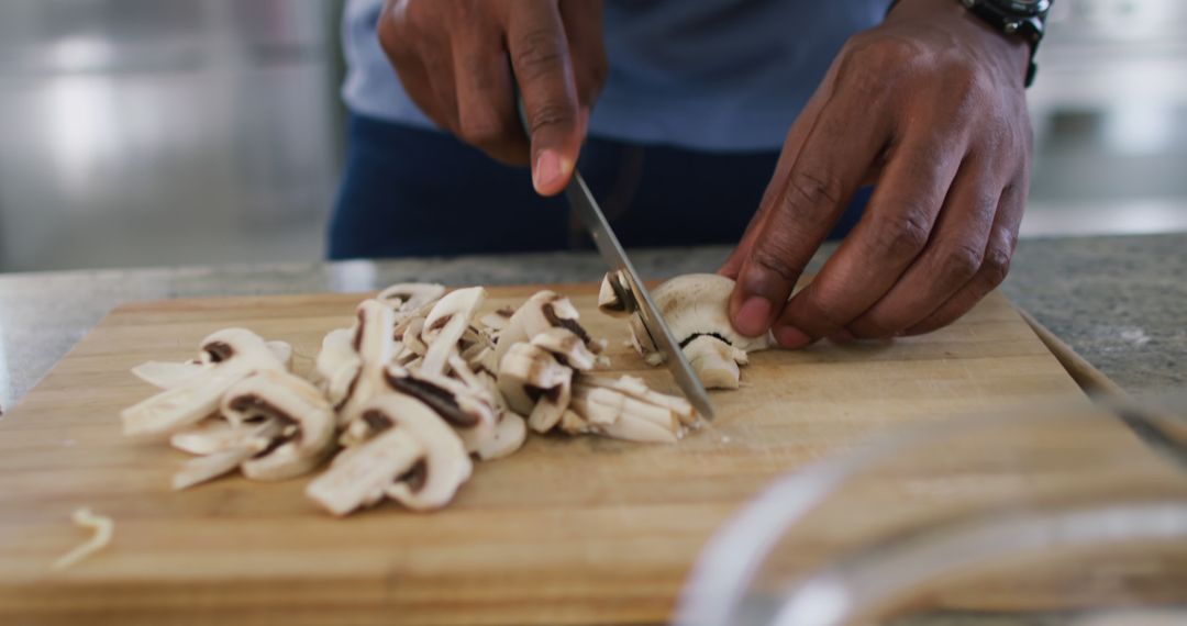 Man Slicing Mushrooms on Wooden Cutting Board in Kitchen - Free Images, Stock Photos and Pictures on Pikwizard.com