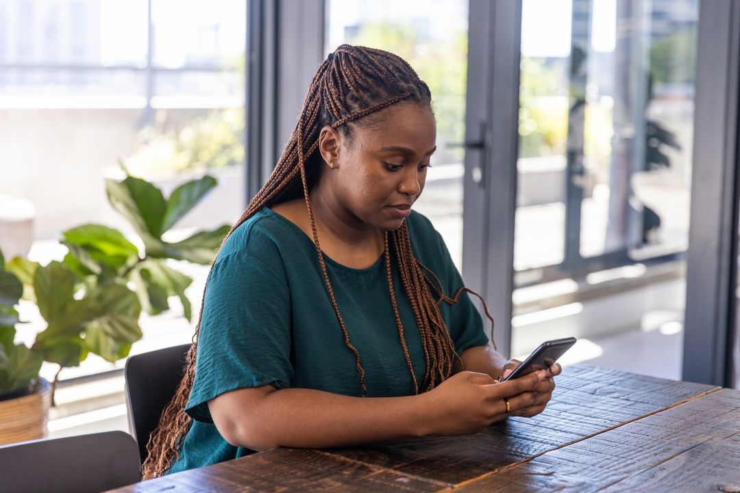 African American Woman Relaxing and Using Smartphone in Modern Room
