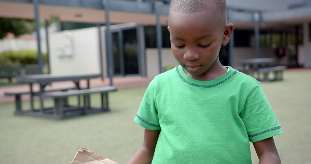 Child Enjoying Creative Play with Cardboard in School Playground