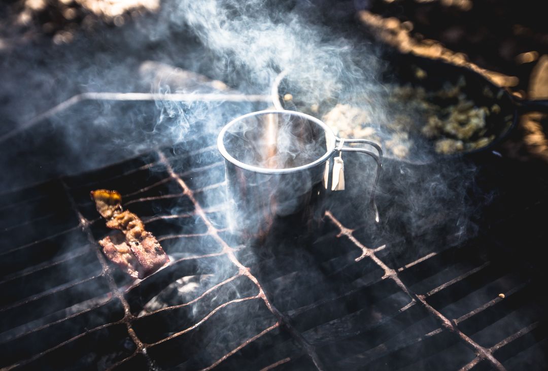 Campfire Grill Smoking with Metal Mug and Sizzling Bacon Strip