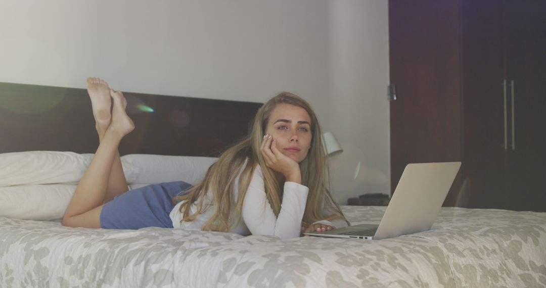 Young Woman Relaxing on Bed Using Laptop in Comfortable Bedroom - Free Images, Stock Photos and Pictures on Pikwizard.com